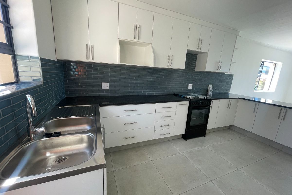 Modern kitchen featuring white cabinetry, black granite countertops, subway tile backsplash, and a double bowl stainless steel sink.