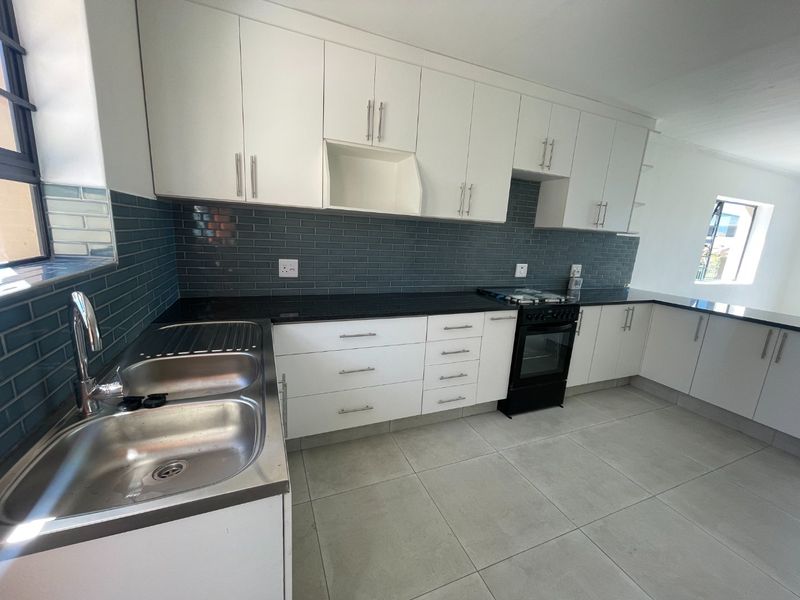 Modern kitchen featuring white cabinetry, black granite countertops, subway tile backsplash, and a double bowl stainless steel sink.