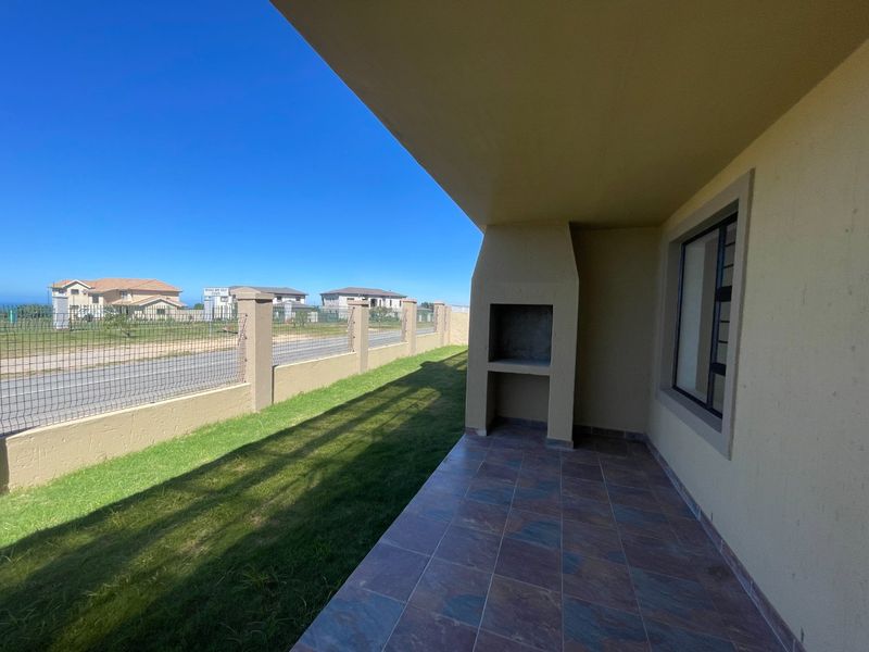 A covered patio featuring a built-in braai and tiled flooring, overlooking a private garden area with boundary walling.