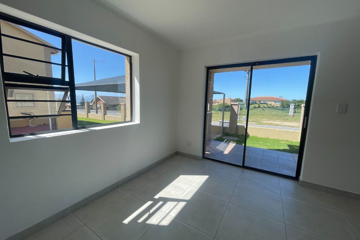 Bright and airy living area featuring neutral tiled flooring, large windows with security bars, and a sliding glass door leading to the exterior.