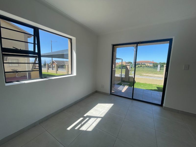 Bright and airy living area featuring neutral tiled flooring, large windows with security bars, and a sliding glass door leading to the exterior.