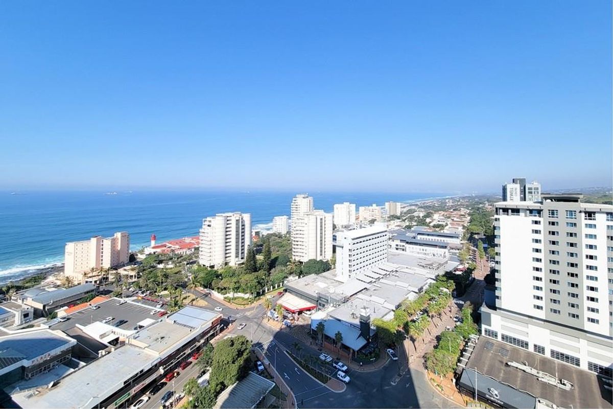 Elevated aerial view overlooking the coastal cityscape, surrounding urban infrastructure, and the ocean horizon.