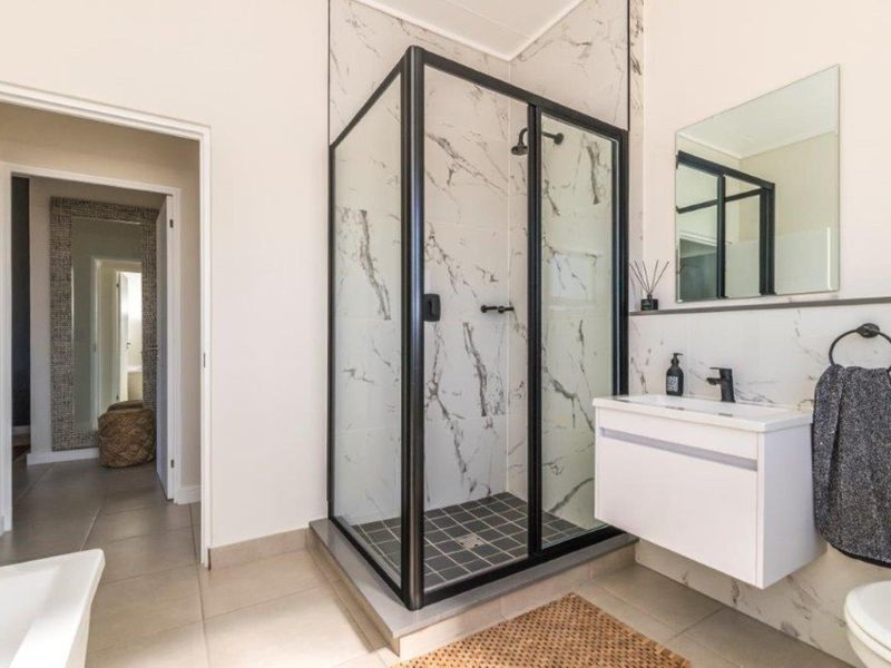 Modern bathroom featuring a glass-enclosed shower with marble-look tiling, a wall-mounted vanity, and contemporary fixtures.