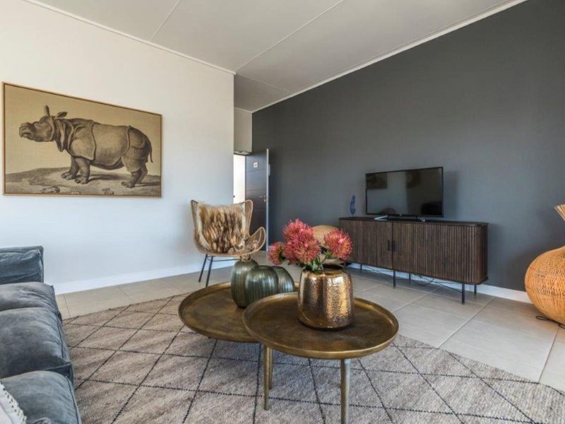A well-maintained living room featuring neutral tiled flooring and a striking dark grey accent wall, creating a modern and inviting atmosphere.