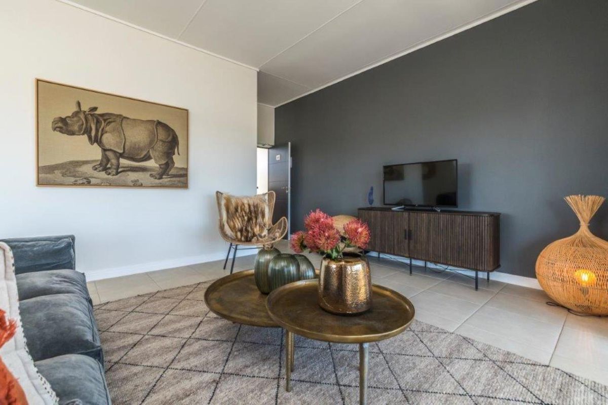 A well-maintained living room featuring neutral tiled flooring and a striking dark grey accent wall, creating a modern and inviting atmosphere.