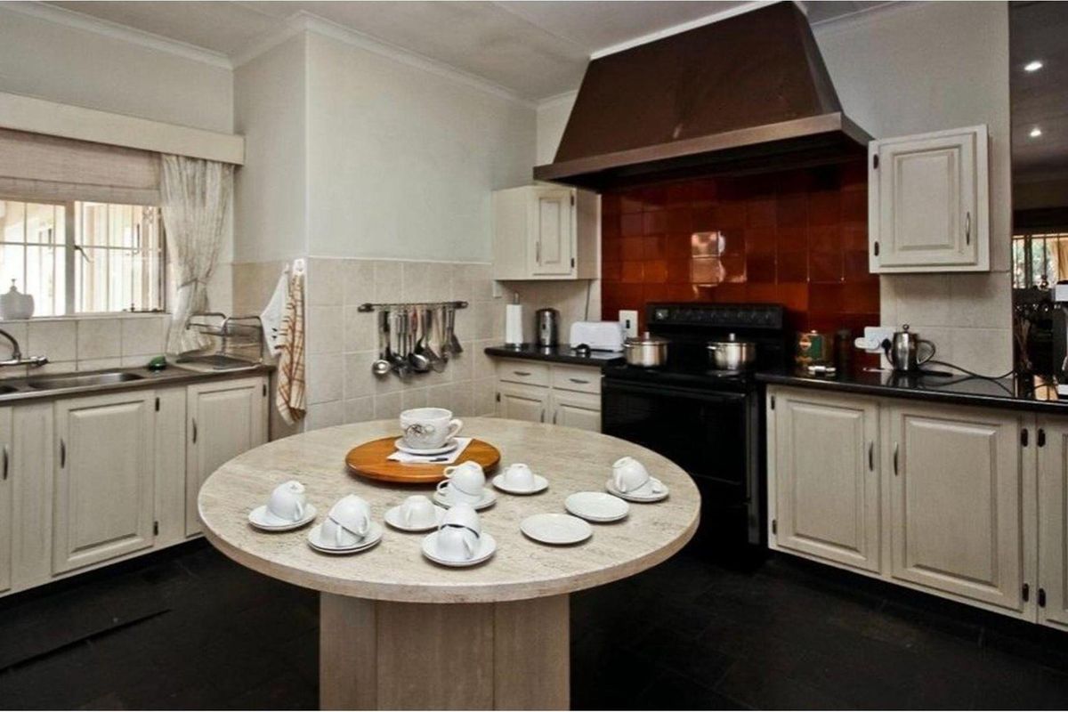 A traditional kitchen featuring cream-colored cabinetry, a dark stone-look island, a built-in extractor hood, and a dark tiled backsplash.