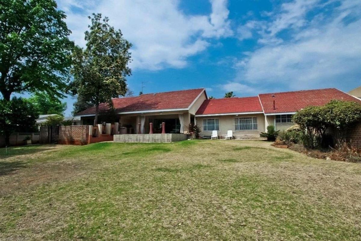 Rear view of the house featuring a tiled roof, a covered patio area, and a spacious backyard garden.