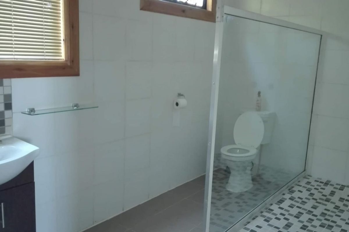 A functional bathroom featuring a vanity basin, a glass-enclosed shower, and tiled finishes throughout, providing a clean and practical space.