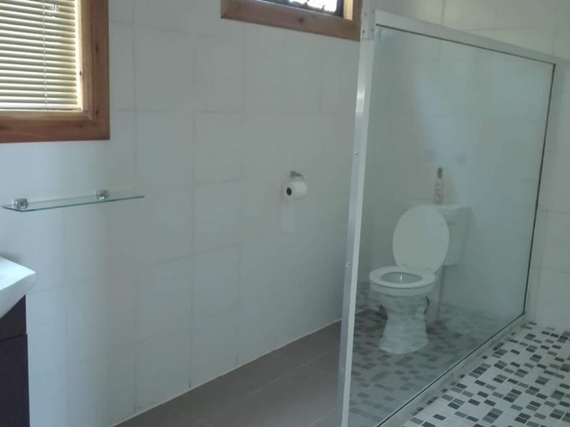 A functional bathroom featuring a vanity basin, a glass-enclosed shower, and tiled finishes throughout, providing a clean and practical space.