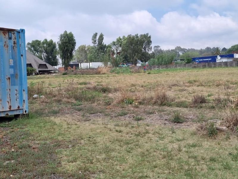 Expansive industrial land plot featuring an existing shipping container, offering significant potential for development or storage use in an industrial zone.