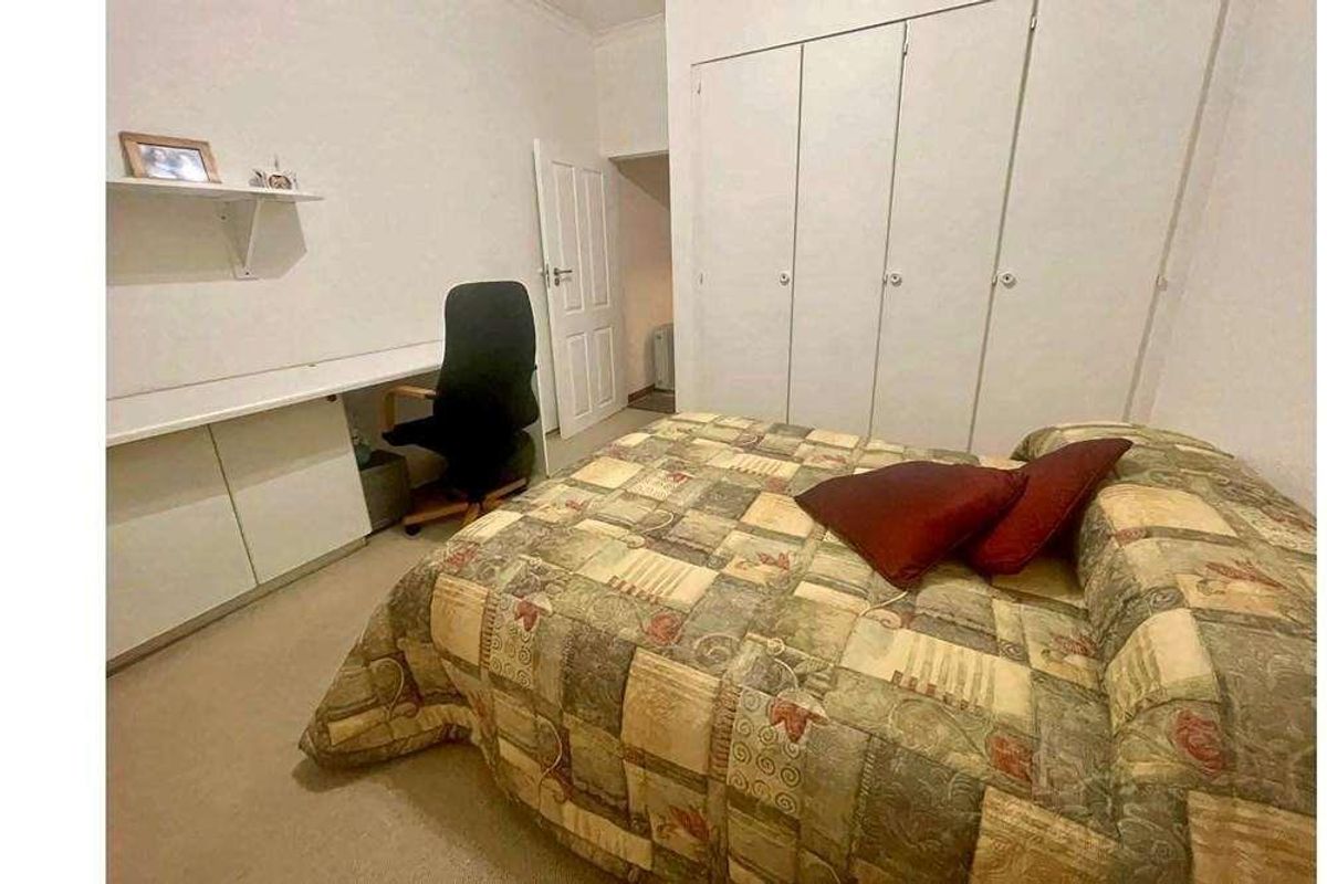 A bedroom featuring built-in wardrobes and a fitted desk area with shelving, providing functional storage and workspace.