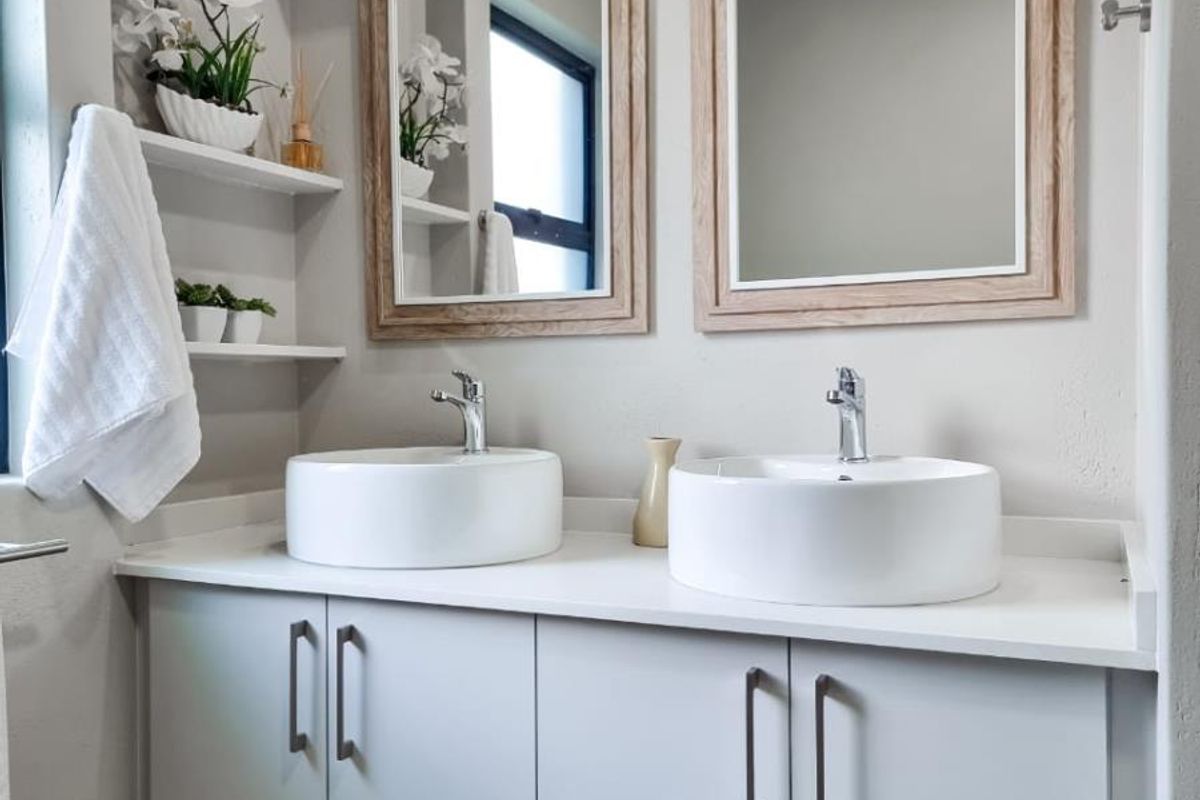 Modern bathroom vanity featuring a floating cabinet, dual vessel sinks, chrome faucets, and matching framed mirrors.