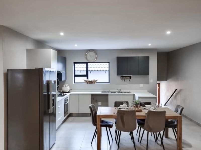 Modern open-plan kitchen and dining area featuring sleek cabinetry, integrated appliances, and neutral floor tiles, creating a functional and cohesive living space.