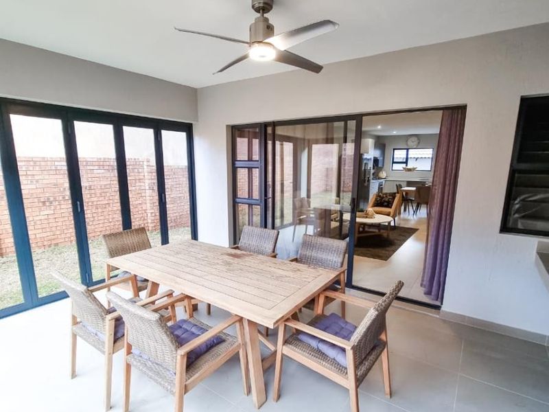 A covered patio featuring large glass sliding doors, tiled flooring, and a ceiling fan, providing a seamless transition to the interior living space.