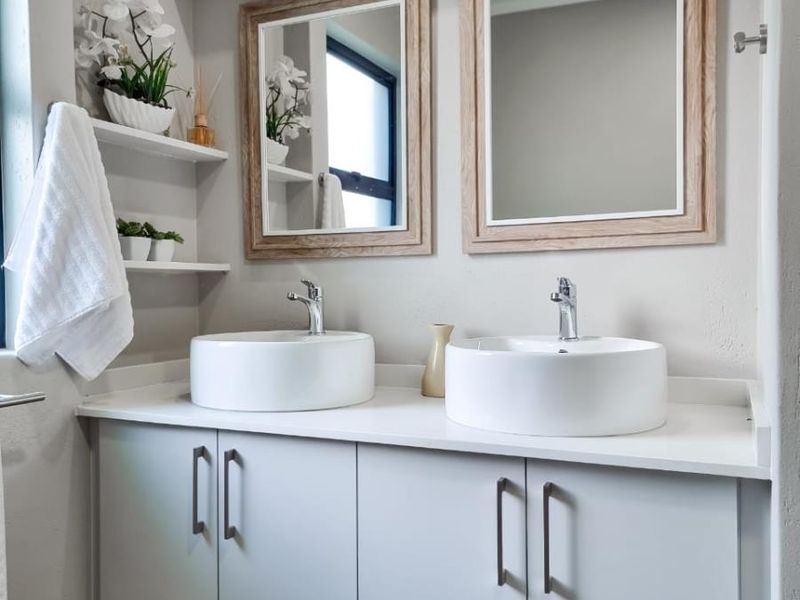 Modern bathroom vanity featuring a floating cabinet, dual vessel sinks, chrome faucets, and matching framed mirrors.