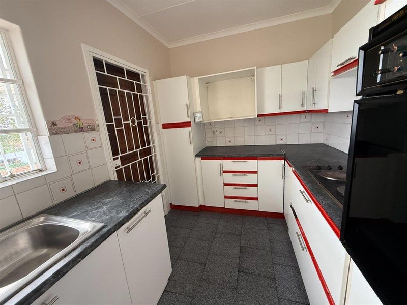 A functional kitchen featuring built-in cabinetry, laminate countertops, a built-in oven, and a hob, with a tiled backsplash and a security gate.