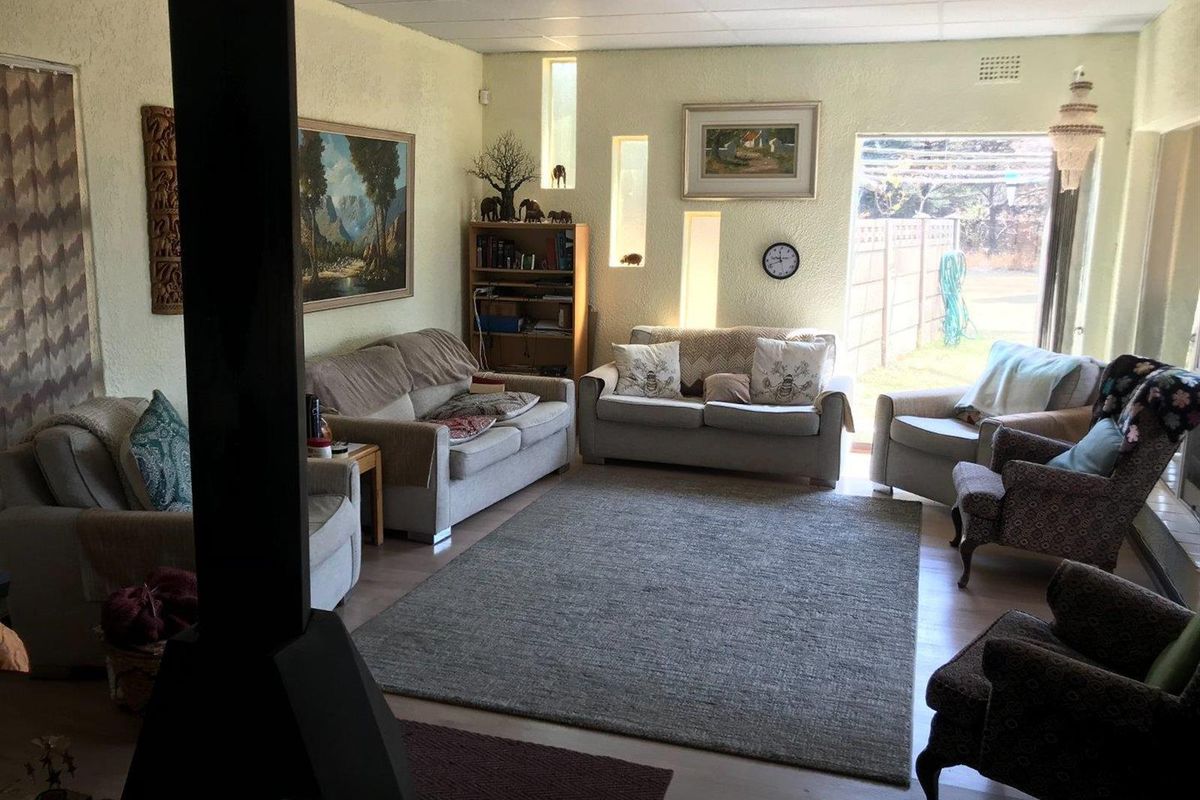 A spacious living room featuring a central freestanding fireplace, laminate flooring, and unique vertical slit windows providing natural light.