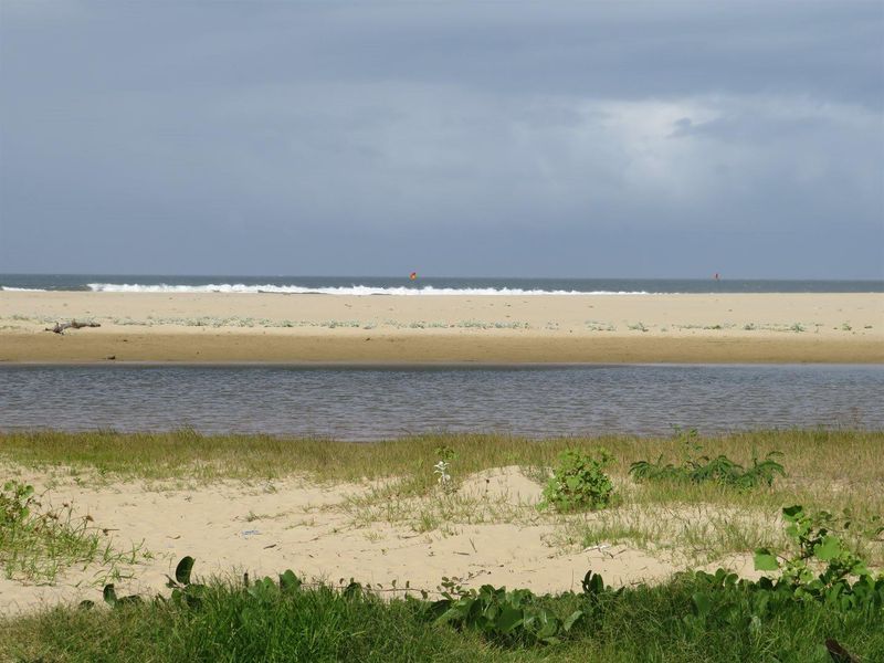 A scenic view of the sandy beach, coastal dunes, and ocean waves, showcasing the natural landscape of the vacant residential property.