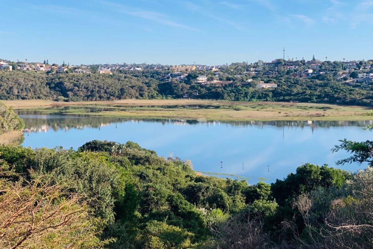 A scenic elevated view overlooking a tranquil lagoon and surrounding natural landscape, showcasing the peaceful environment of the vacant residential land.