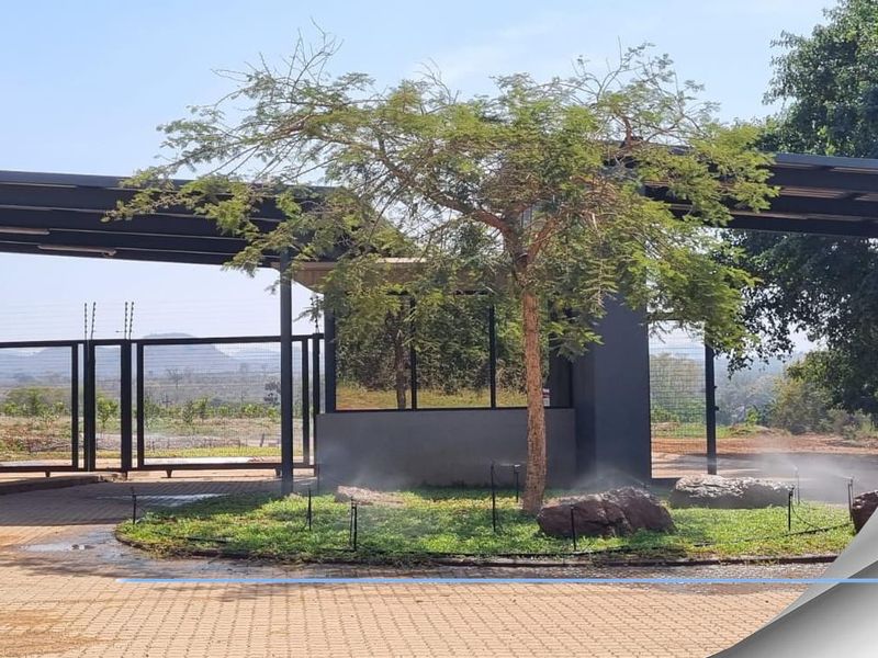 Entrance gate and security guardhouse for the residential estate, featuring paved driveway, modern metal structure, and landscaped garden area.