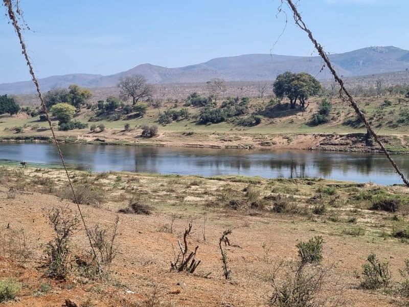 A scenic view of a river flowing through a natural landscape with rolling hills in the background.