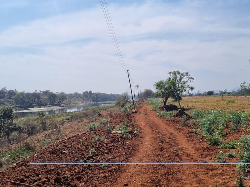 A view of the vacant residential land featuring a dirt access path, natural vegetation, and proximity to a riverbank.