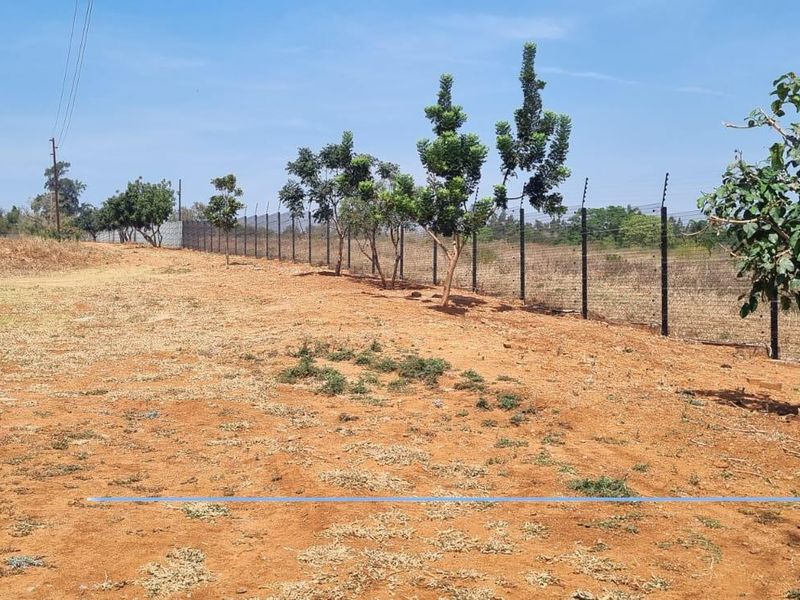 A view of the vacant residential land featuring perimeter wire fencing and established trees along the boundary line.