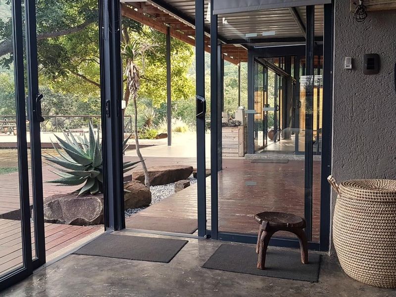 A seamless transition from an interior concrete-floored space to an expansive outdoor wooden deck, featuring large sliding glass doors and natural garden views.