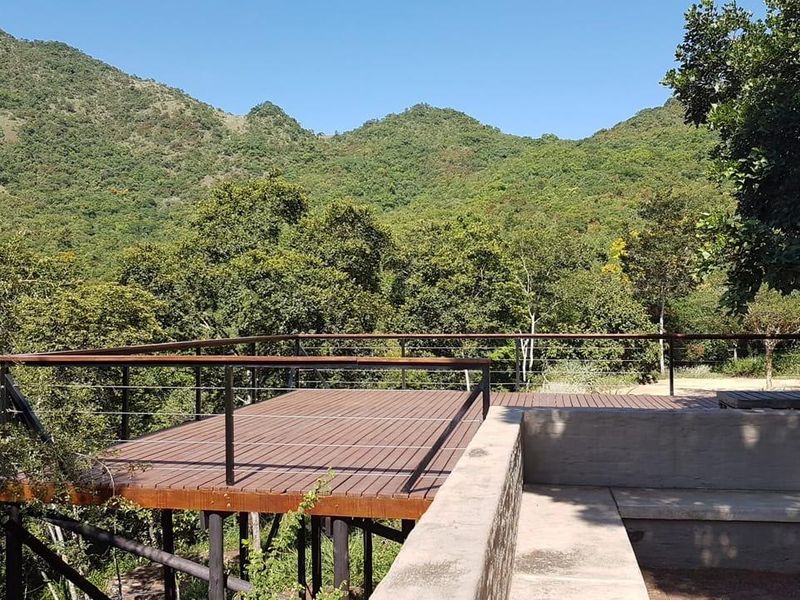 An elevated timber deck featuring a modern metal railing, offering expansive views of the surrounding natural landscape and mountain range.