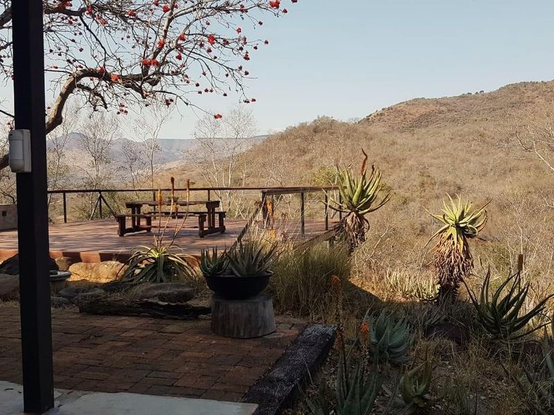 An elevated outdoor deck area featuring a metal railing, offering expansive views of the surrounding natural landscape and hills.