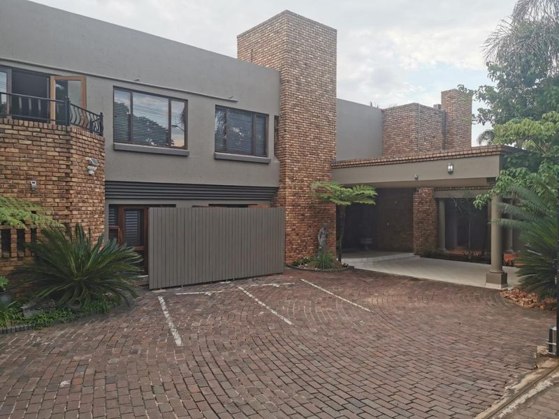 Front elevation of a multi-story residence featuring a brick facade, paved driveway, and a covered entrance area.