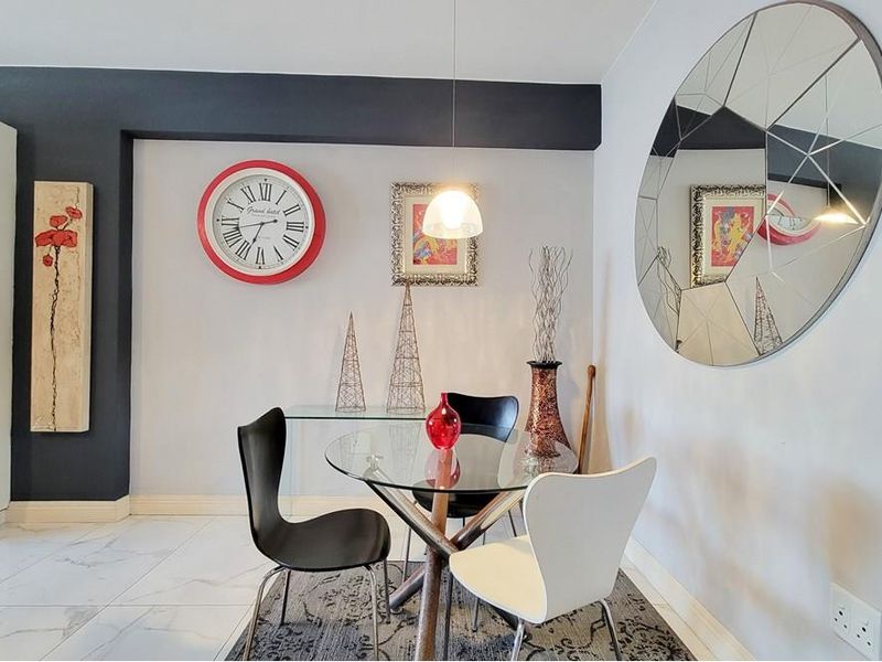 A bright dining area featuring modern tiled flooring, neutral wall tones with a dark accent beam, and contemporary pendant lighting.