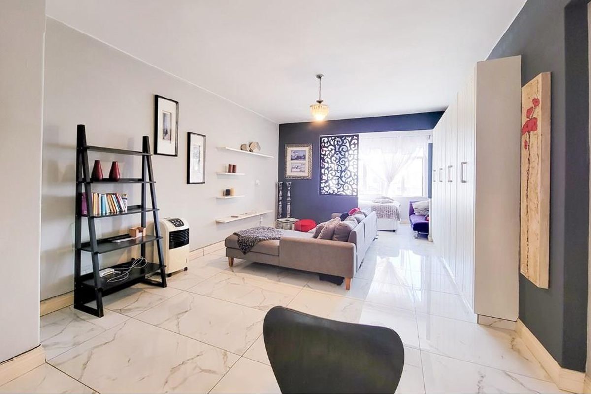Spacious living area featuring polished marble-look floor tiles, extensive built-in storage cabinetry, and a decorative feature wall screen.