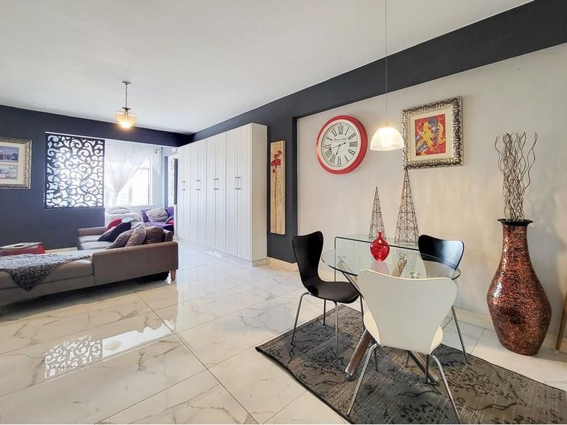 Spacious open-plan living and dining area featuring polished marble-look floor tiles, modern built-in cabinetry, and contemporary pendant lighting.