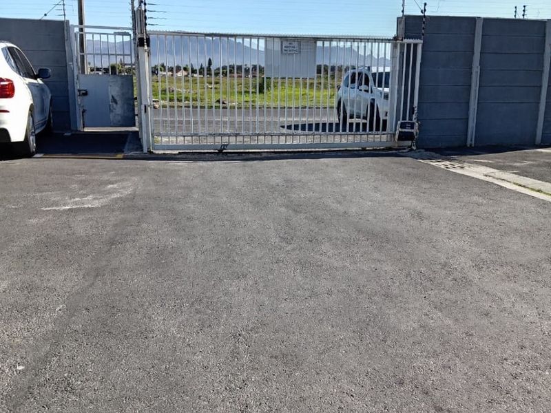 Front entrance view of the property featuring a sliding security gate, electric fencing, and a precast concrete boundary wall.