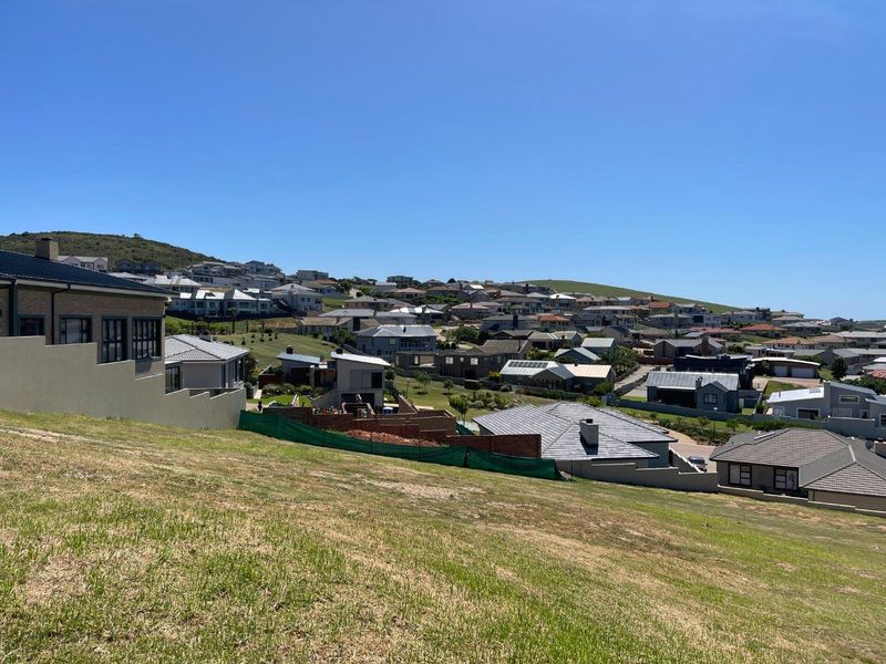 A wide-angle view overlooking a residential estate with sloped terrain and surrounding neighborhood homes.