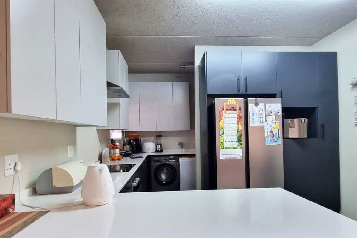 Modern kitchen featuring two-tone cabinetry, stone countertops, a breakfast bar, and integrated space for appliances.