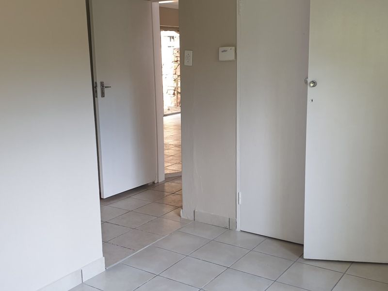 A neutral, empty hallway featuring tiled flooring and multiple internal doors, providing access to adjacent rooms within the apartment.