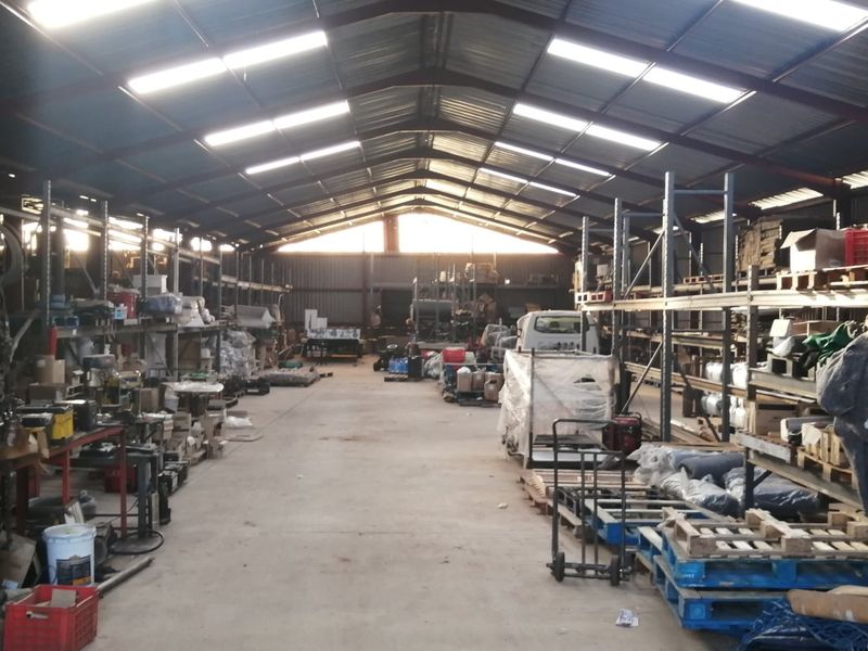Large industrial-style farm shed featuring high-pitched corrugated metal roofing, skylights, and extensive heavy-duty steel racking systems for storage.
