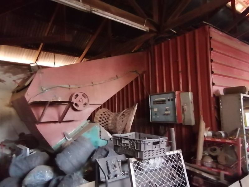 A large industrial utility space on the farm featuring heavy-duty processing machinery and exposed timber roof trusses.