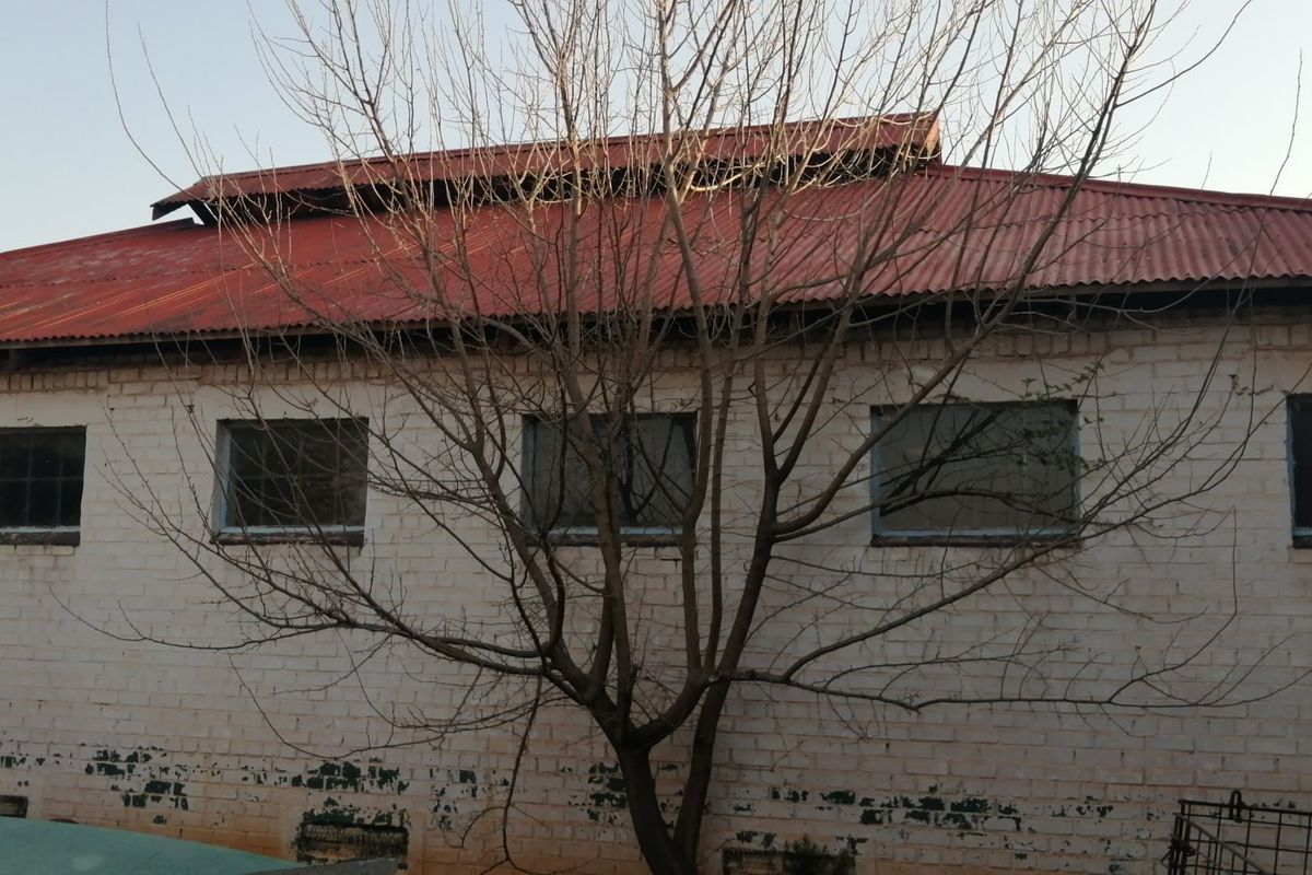 Exterior view of a farm building featuring a corrugated metal roof and painted brick facade with multiple windows.