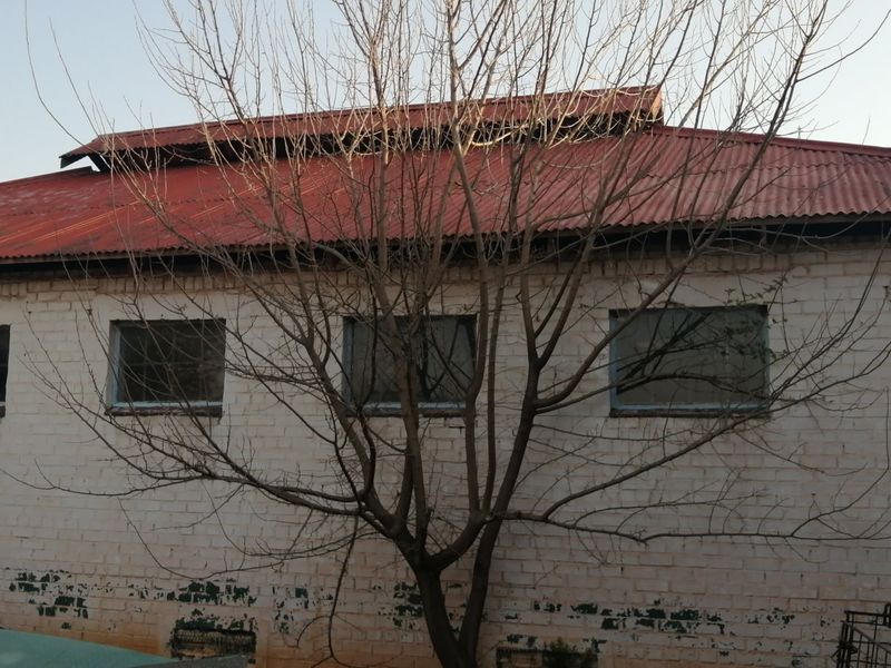 Exterior view of a farm building featuring a corrugated metal roof and painted brick facade with multiple windows.