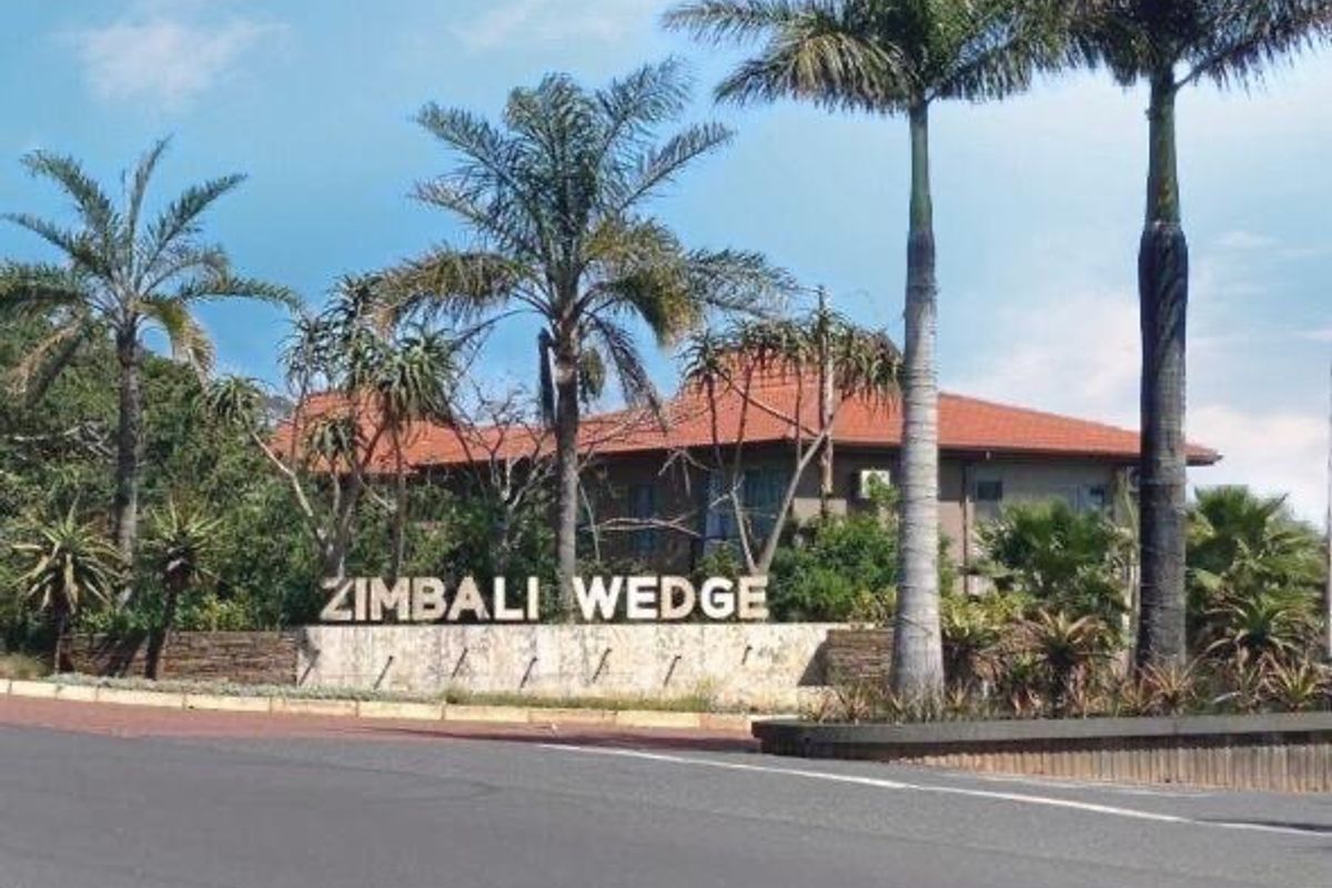 Street view of the Zimbali Wedge estate entrance featuring established palm trees and stone signage.