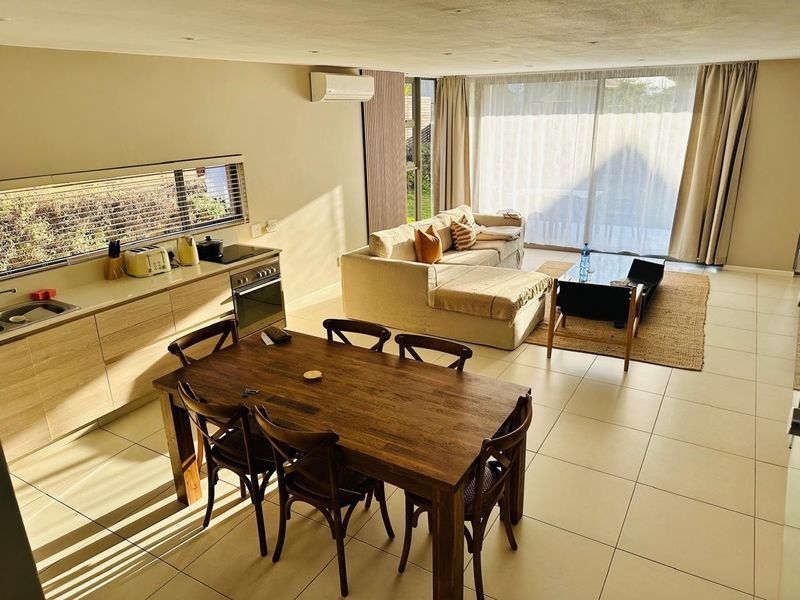 Spacious open-plan living, dining, and kitchen area featuring modern cabinetry, tiled floors, and large sliding doors providing ample natural light.