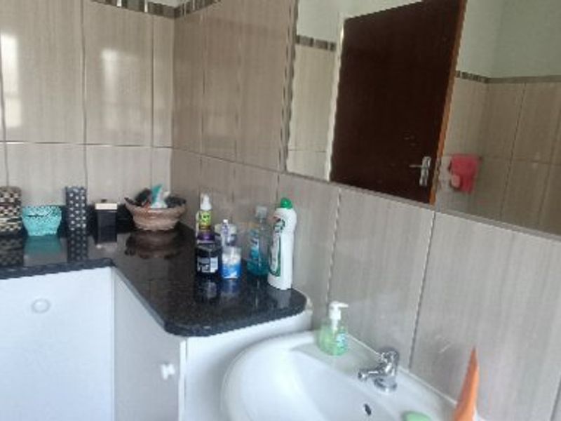 A functional bathroom featuring a vanity cabinet with a granite countertop, pedestal basin, and neutral wall tiling.
