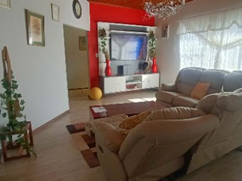 A living room featuring laminate flooring, a timber ceiling, and a built-in media unit with a red accent wall.
