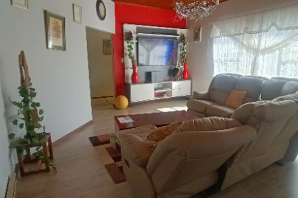 A living room featuring laminate flooring, a timber ceiling, and a built-in media unit with a red accent wall.