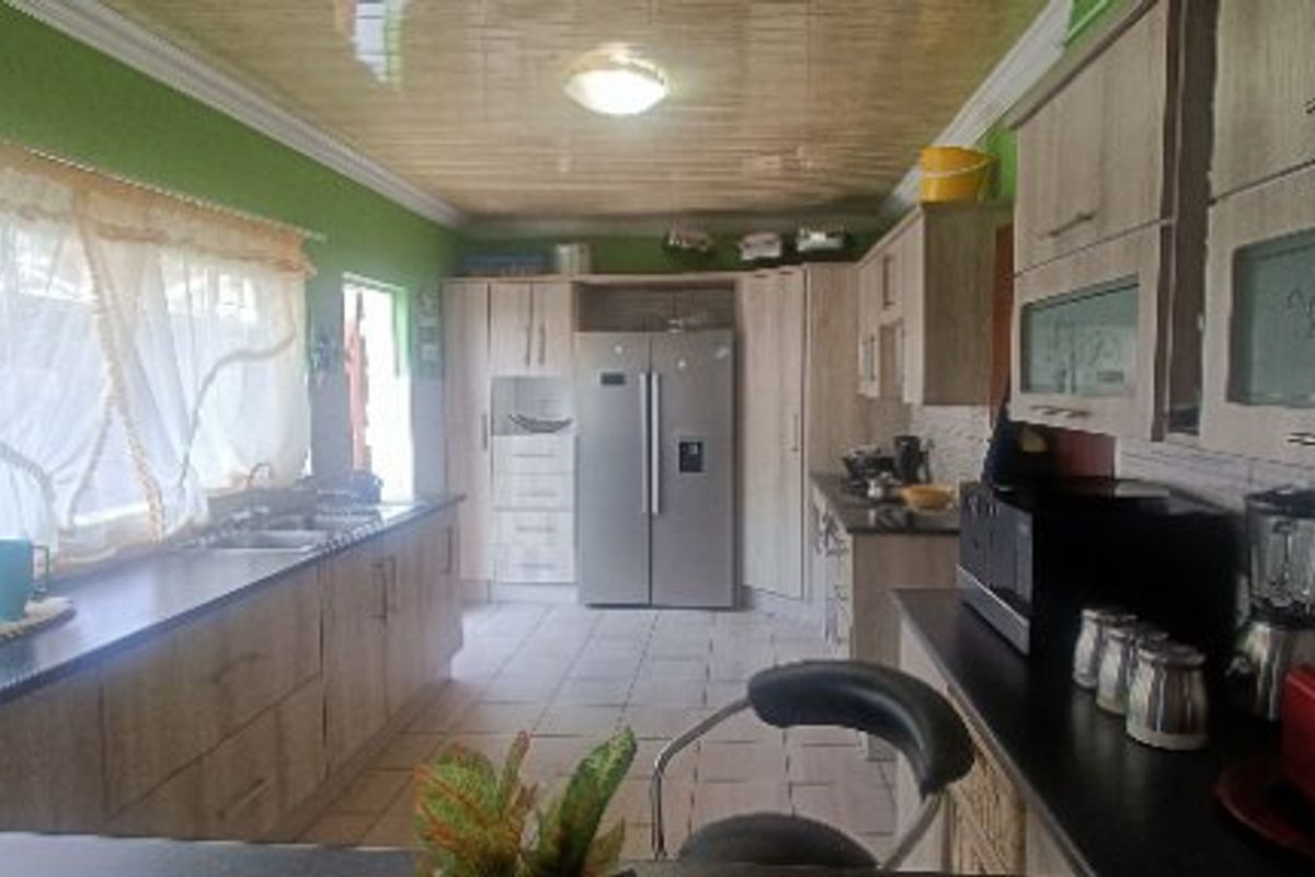 A functional kitchen featuring extensive built-in cabinetry, laminate countertops, a double sink, and tiled flooring with a coved ceiling.
