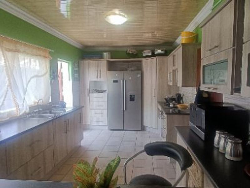A functional kitchen featuring extensive built-in cabinetry, laminate countertops, a double sink, and tiled flooring with a coved ceiling.