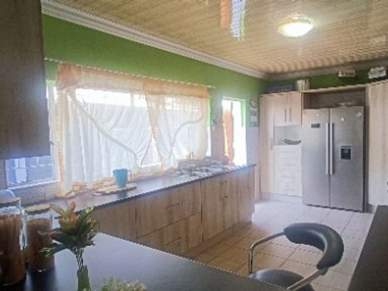 A functional kitchen featuring wood-look cabinetry, laminate countertops, tiled flooring, and a large double-door refrigerator.